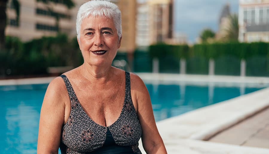 mulher com pele madura de maiô na piscina.