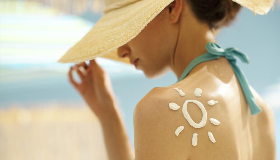 Mulher com protetor solar nas costas.