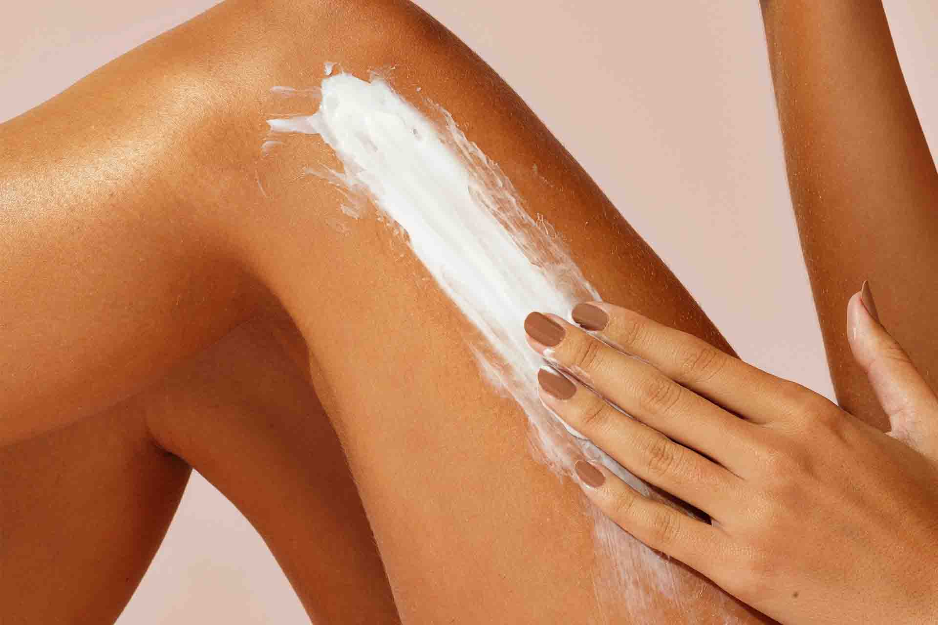 como cuidar da pele do corpo - mulher branca passa creme hidratante na pele
